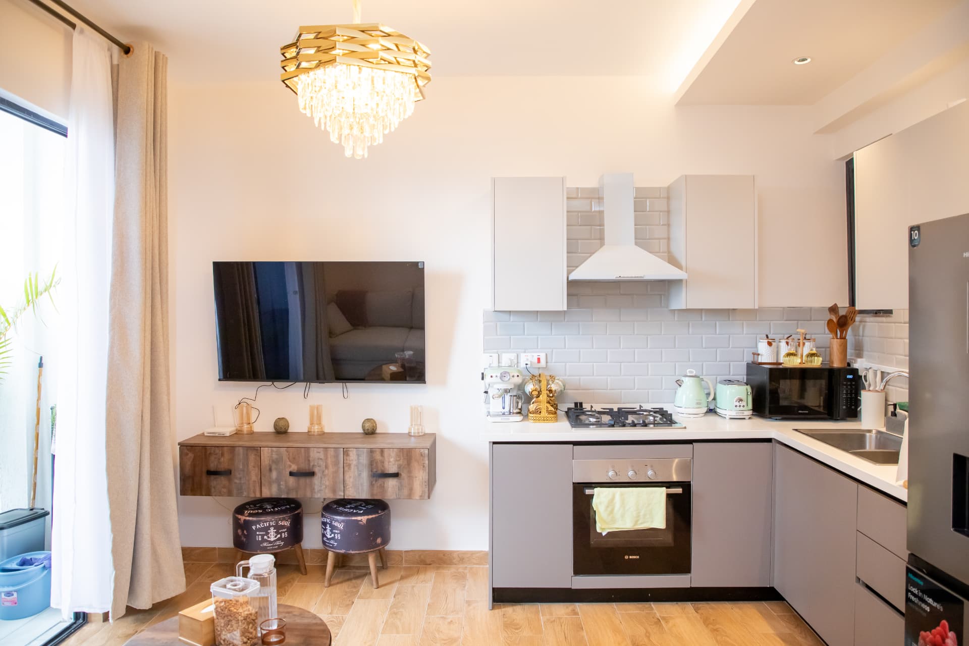 Open-plan living room with chandelier, TV wall and dining area at Aurevia Homes, Kilimani